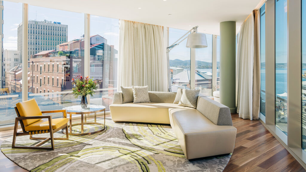 a couch, accent chair, side table, and lamp next to floor-to-ceiling windows in a room at The Westin Yantai