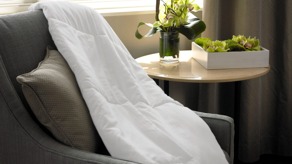 a Westin Travel Blanket draped over an armchair, with a side table next to it