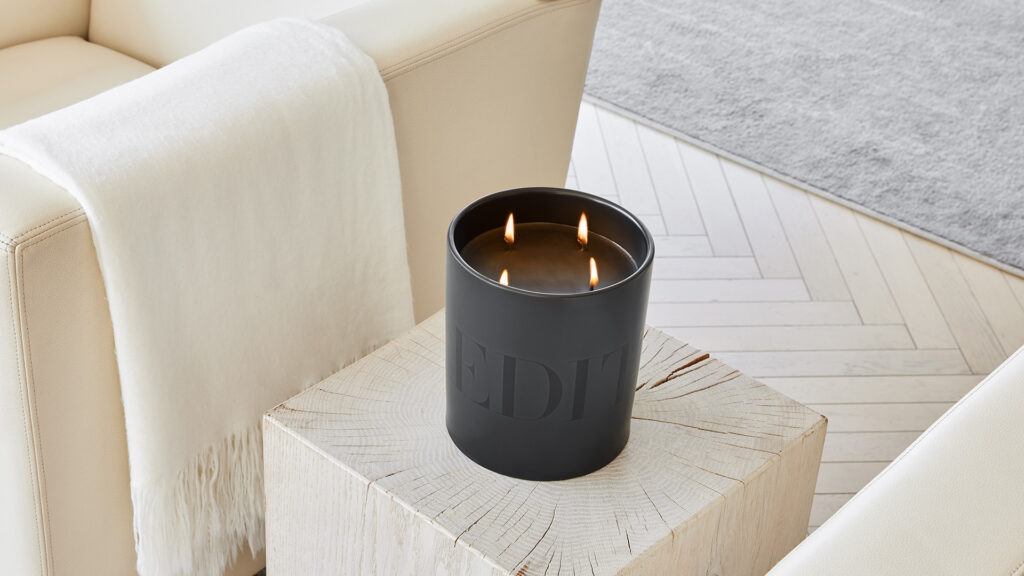 a lit EDITION Candle on a cream-colored side table
