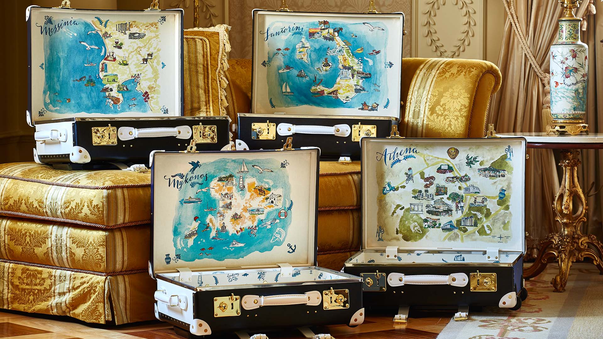 four open trunk-style suitcases sit open, featuring different illustrated maps on the inside of the lid