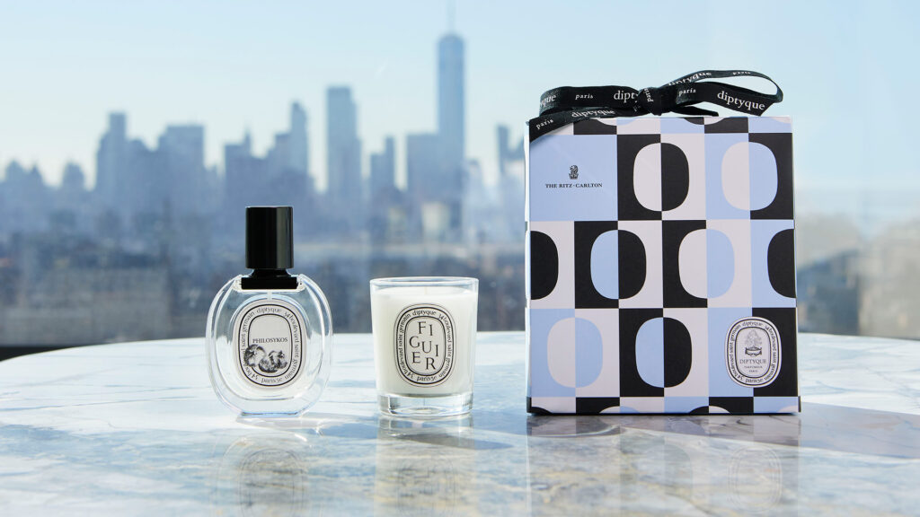 a Diptyque for The Ritz-Carlton Gift Set arranged on a table with a city skyline in the distance
