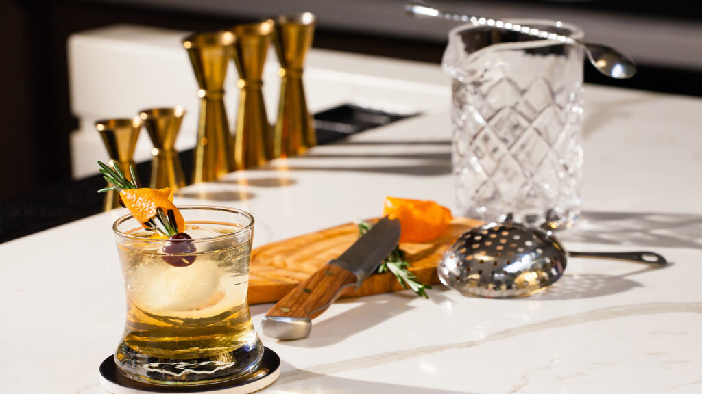 two glasses and a mixing set from The Marriott Hotels Bourbon Collection, sitting on a white counter