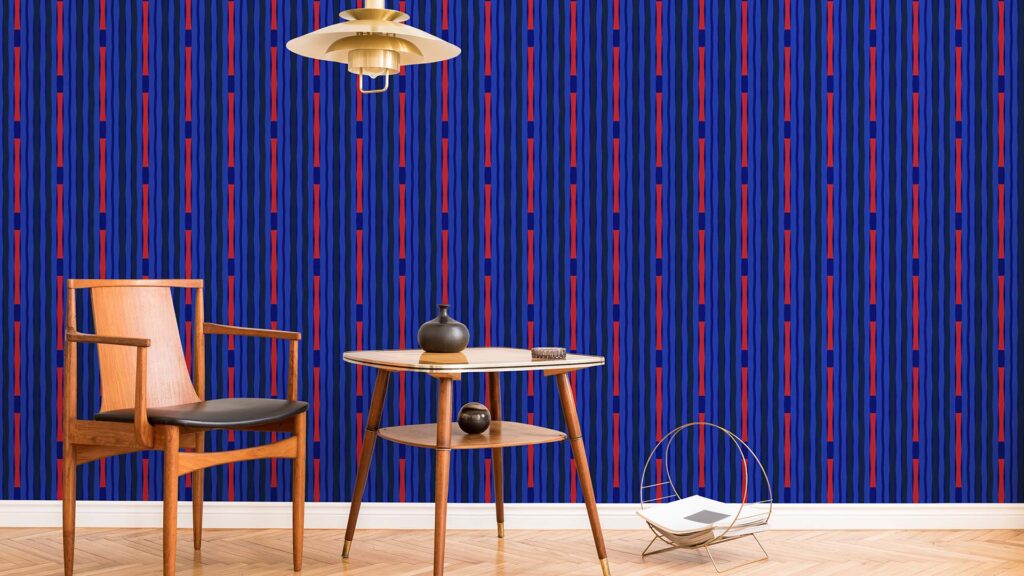 Le Méridien La Fête wallpaper in cobalt blue with red bowtie-shaped stripes covers a wall, with a table and side table in front of it
