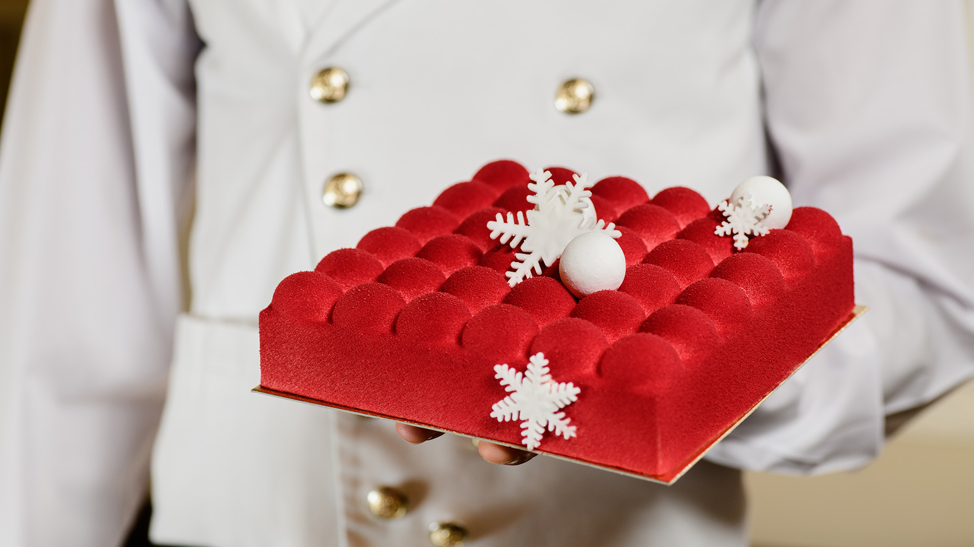 a chef in white carries a red Christmas Cake served at Hotel Bristol, a Luxury Collection Hotel, Warsaw