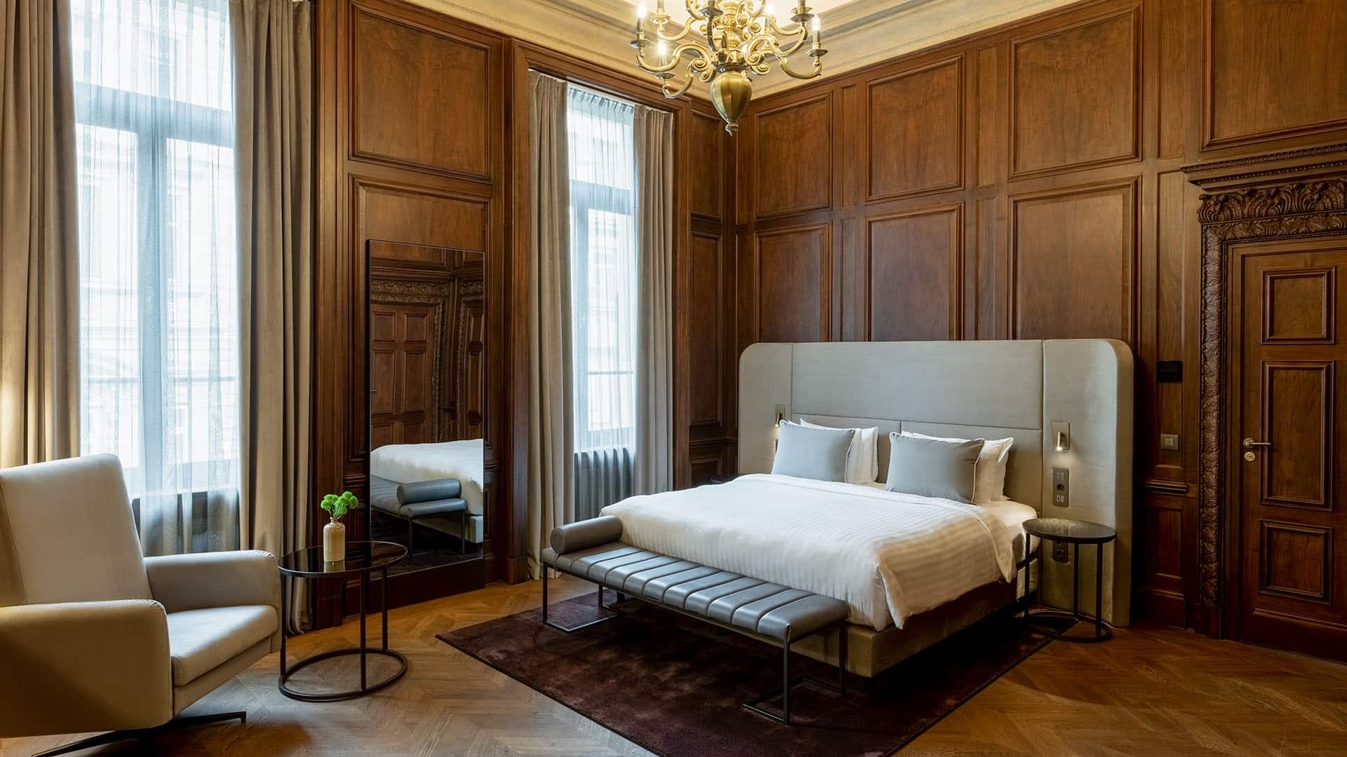 bed and seating area of a wood-paneled room at The Marmorosch Bucharest, Autograph Collection