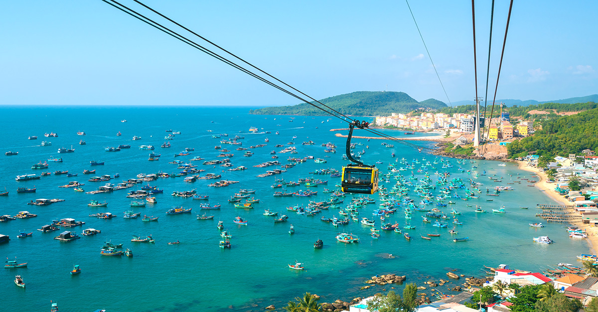 view of a cable car hanging above a beach and nearby boats