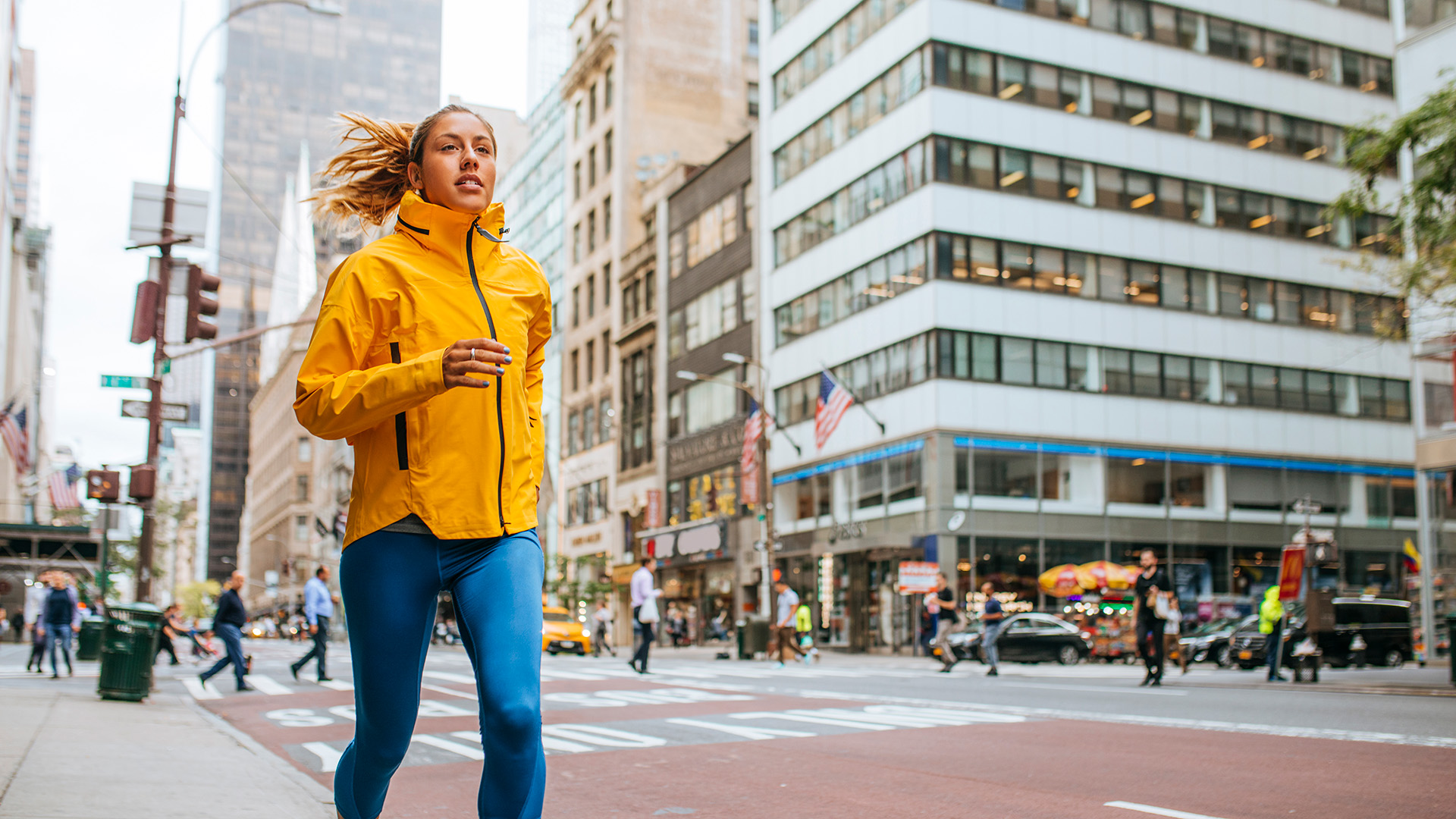 A woman in a yellow jacket jogging in New York City