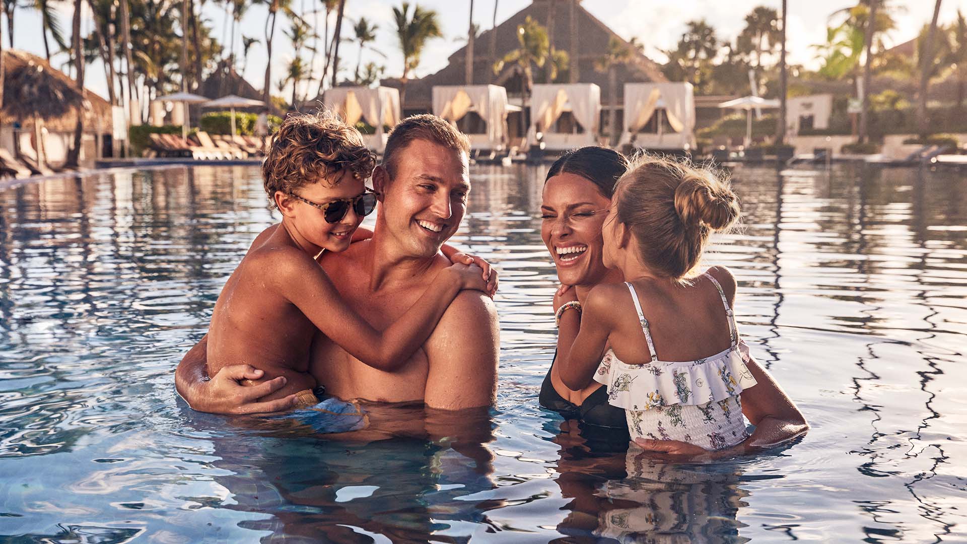 Two parents and two children embrace in a pool