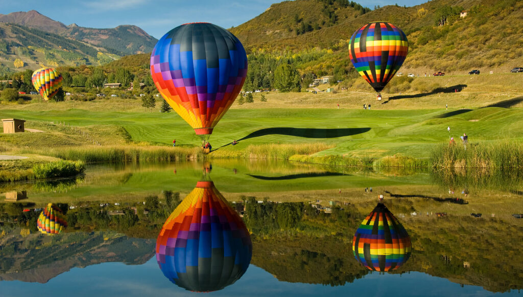 Three colorful hot air balloons floating at the Snowmass Balloon Festival in Aspen, Colorado