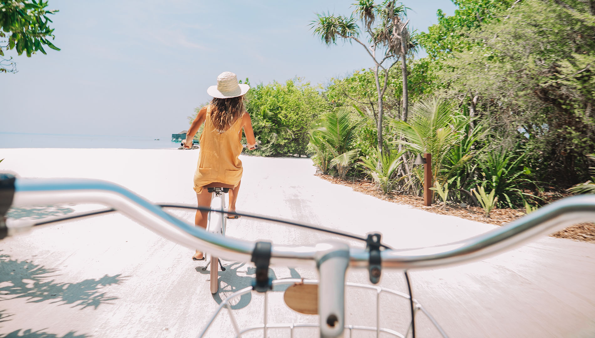 A woman bikes on a sandy trail in the Maldives