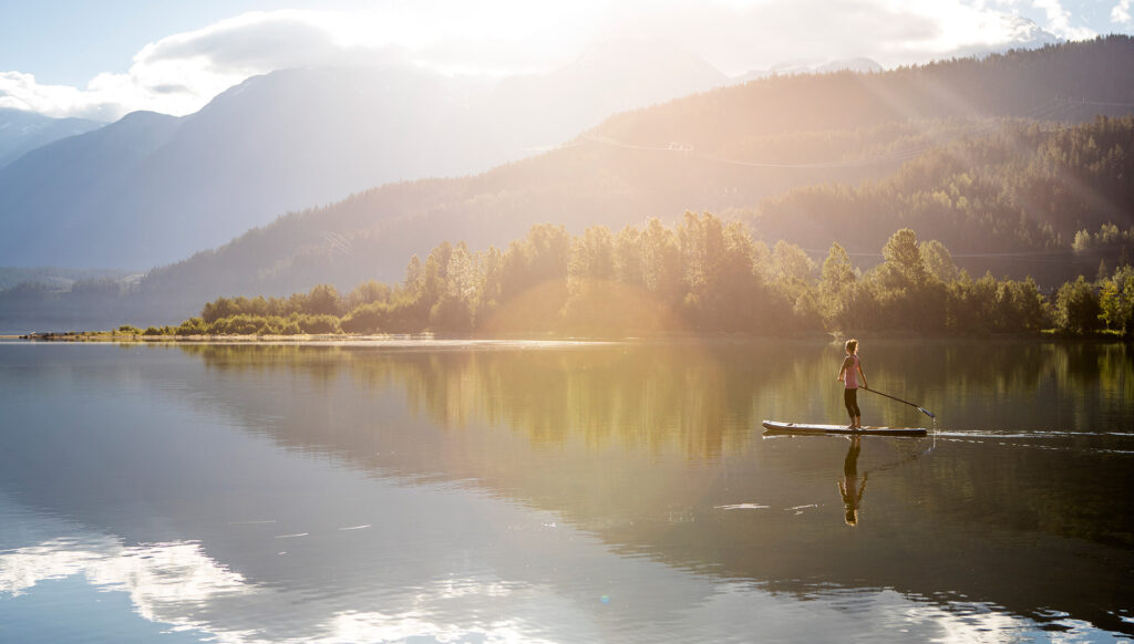 A woman standing on a paddleboard in Whistler, Canada