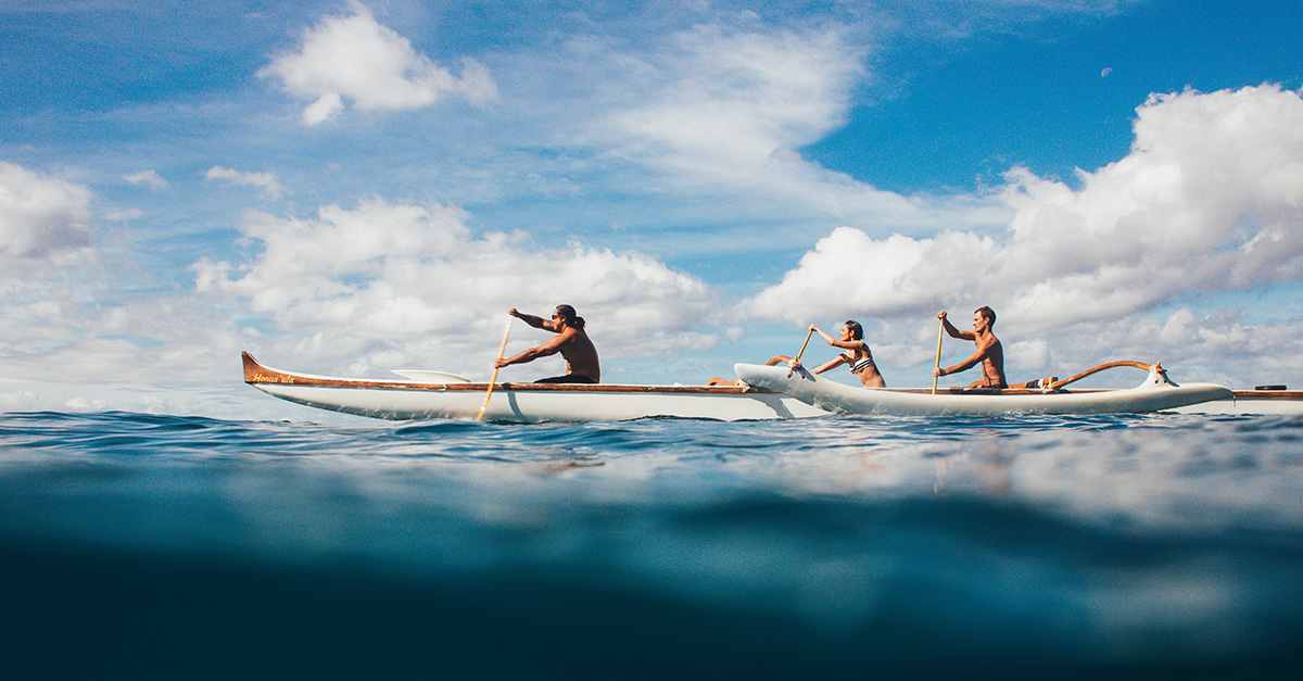 Three people rowing on an outrigger boat