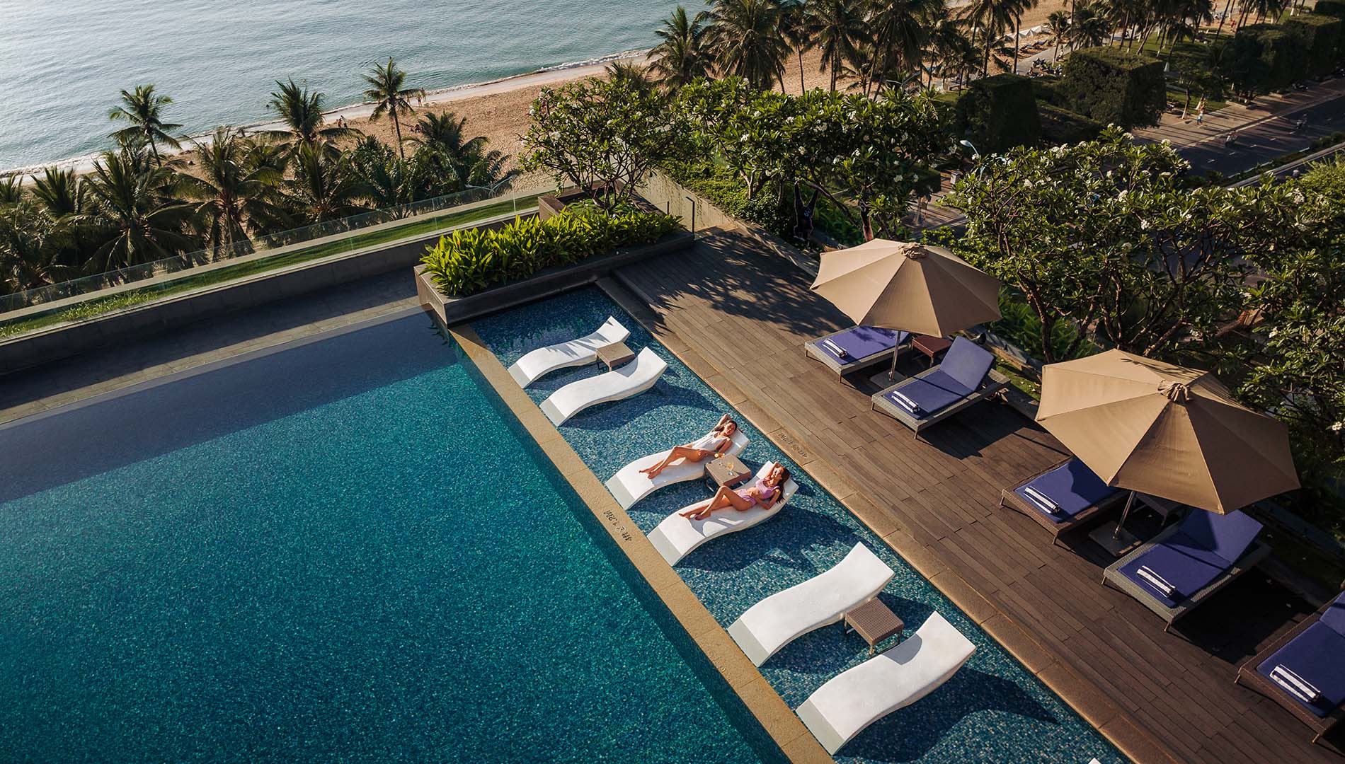 Aerial view of two people sunning on lounge chairs next to a swimming pool in Nha Trang, Vietnam