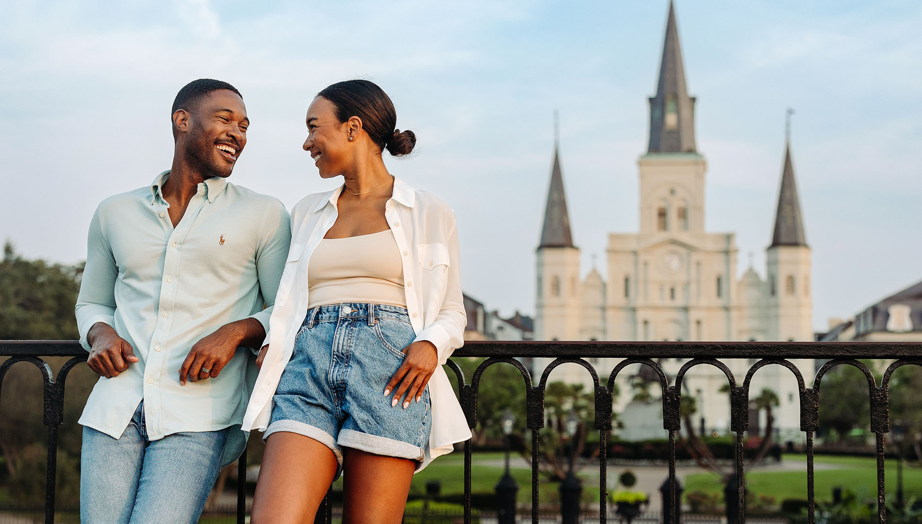 A smiling couple leans on a fence in New Orleans, Louisiana