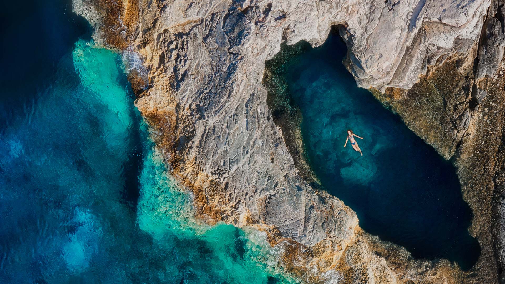 Aerial view of a woman floating in a natural pool in Croatia