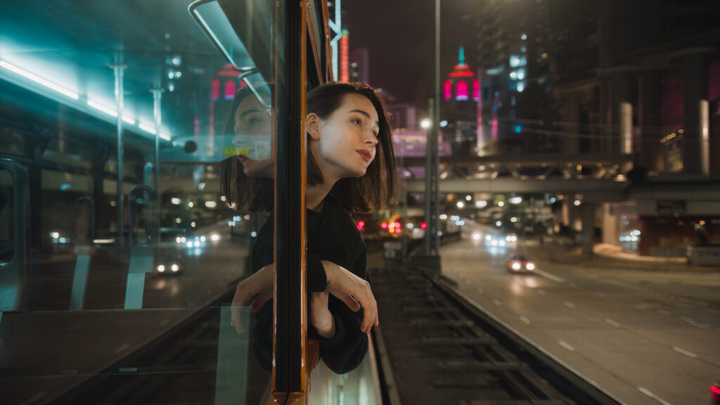 woman riding a double decker tram in Hong Kong.
