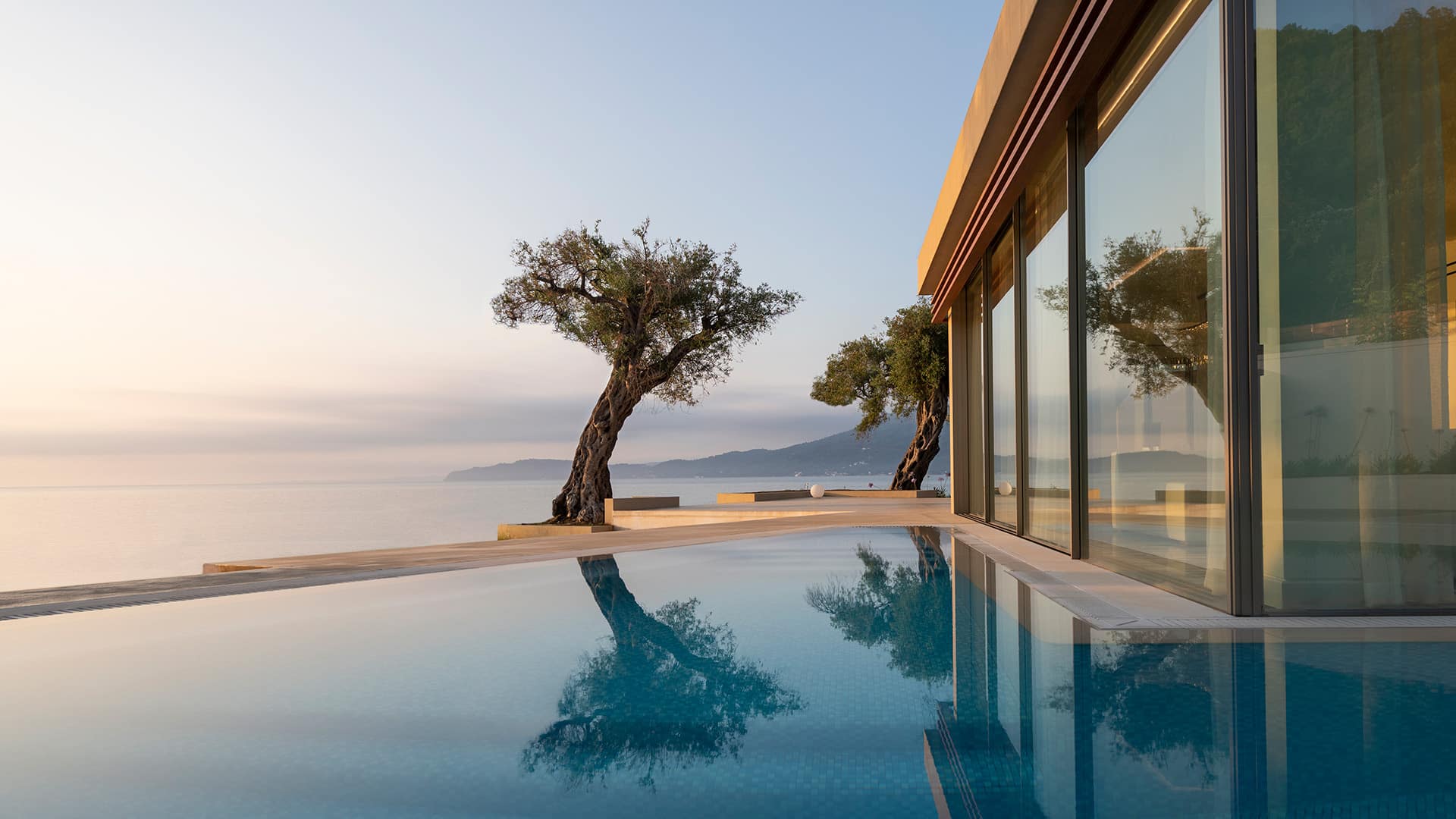 a serene pool and tree overlooking the water at Domes Miramare, a Luxury Collection Resort, Corfu