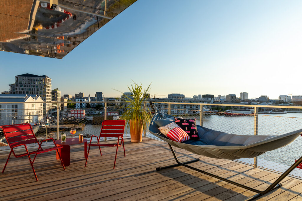 view of a guestroom terrace with hammock and chairs at the moxy bordeaux