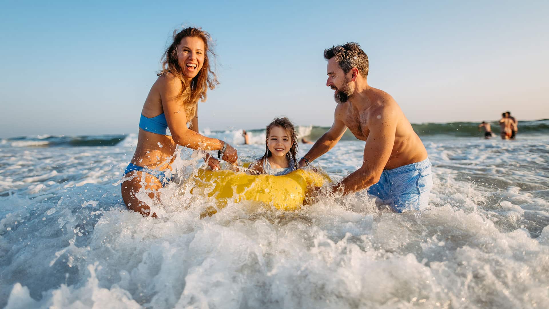 A family splashes in the waves on a beach